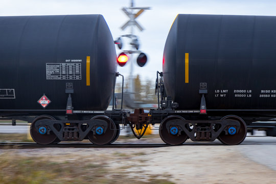 Tank Cars Connected Together Passing a Flashing Railway Crossing