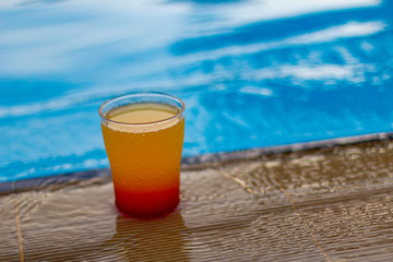 Colorful cocktail on the edge of a bright blue pool.