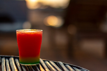 Colorful cocktail on a dark wicker table on the beach in the sunlight with some bokeh