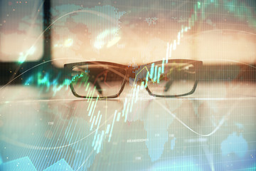 Financial graph hologram with glasses on the table background. Concept of business. Double exposure.