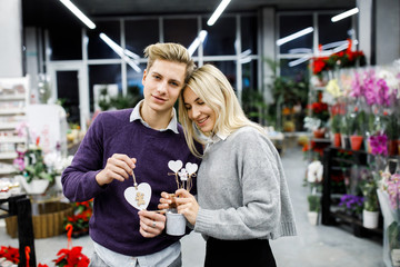Portrait of young man with woman shopping presents in store in time before the winter holidays. Beautiful couple buys gifts for family and friends