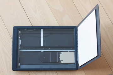 Open flatbed scanner on wooden table. Top view image.