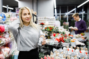 Portrait of young man with woman shopping presents in store in time before the winter holidays. Beautiful couple buys gifts for family and friends