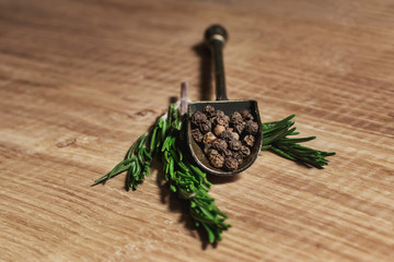 A beautiful vintage scoop with fragrant spices, on green sprigs of rosemary, on a white oak kitchen board. Recipe book with meat dishes and salads. Vintage still life in warm colors.