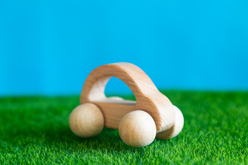 Children's wooden toy car on the grass Wooden car on the green grass blue background