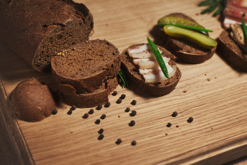 Three sandwiches in the Russian style: with lard, with fish, with pickles and green onions. Still life on a white oak kitchen board. Traditional food for cold regions.