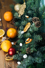 Fototapeta na wymiar fir branches with cones, orange slices, whole tangerines and marshmallows, on the tree. Christmas background