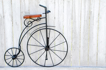 photo of old fashion vintage iron bicycle sitting on white picket fence