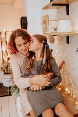 beautiful mother with pink hair with a daughter in the kitchen. mother and daughter in anticipation of christmas. cute mother in a pint sweater