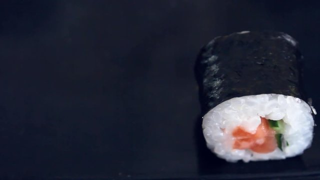 Sushi on the black table. Chopsticks take sushi closeup. Man eats sushi. Lunch at a Japanese restaurant.
