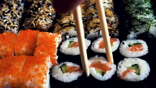 sushi set on a black table. Chopsticks take sushi close-up.