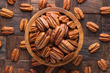 pecan nuts peeled in wooden bowl, top view. - obrazy, fototapety, plakaty