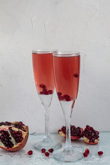 Holiday pomegranate drink. Pink wine. In the background are pomegranate slices. White background. Champagne. New Year. Christmas. Foreground. 