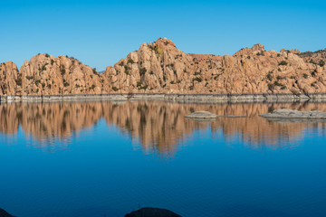 Landscape of intricate rock formations and their reflection in water at Watson Lake Park in Prescott Arizona