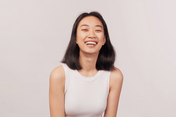 Girl laughs at something funny closes eyes with pleasure. Businesslike young woman Asian appearance...
