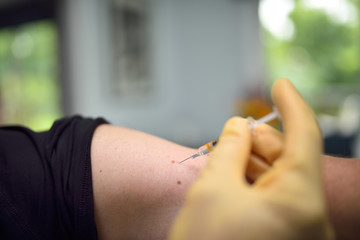 Man receiving a shot in the arm at a health clinic