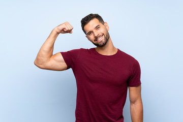 Handsome man over isolated blue background doing strong gesture