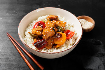 Stir-fry with chicken meat, vegetables and rice in bowl on black background