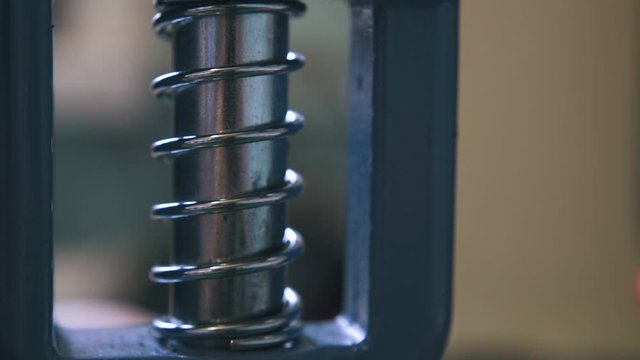CU: Modern silver press machine detail moves setting accessories on leather belt in workshop extreme close view