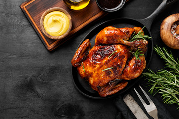 Homemade Roasted chicken with rosemary served in iron pan with sauces.