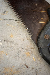 Old rusty saw on a stone floor, close-up.