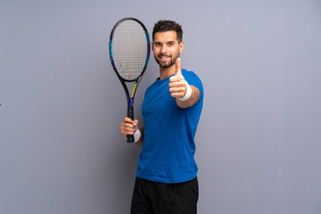Handsome young tennis player man with thumbs up because something good has happened