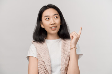 Photo of energetic nice smiling lady pointing finger in eureka sign, having great innovative idea, understanding or solution she has just got. Beautiful young woman wearing t-shirt and pink cardigan