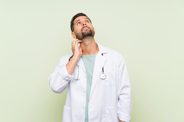 Young doctor man over isolated green wall thinking an idea