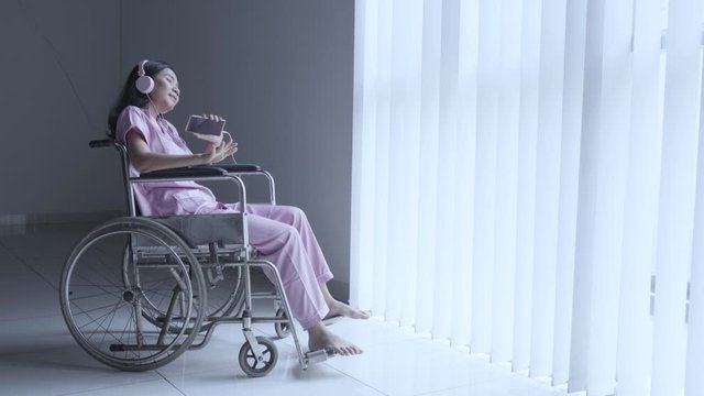 Disabled woman listening music near the window