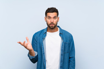 Handsome man over isolated blue background making doubts gesture