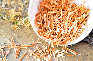 A white plastic bucket of sawdust toppled onto the stone curb and the sawdust spilled onto the ground.