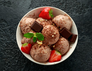Chocolate Ice Cream with dark chocolate bars, strawberry and hazelnuts in a white bowl
