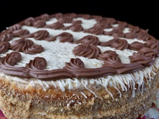 Round cake with cream patterns, on a black background. A sweet birthday present for a teenager. A festive dessert for the whole family. Baking with icing on a plate.