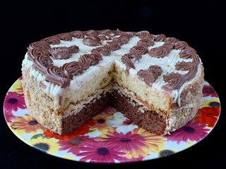 Round cake with cream patterns, on a black background. A sweet birthday present for a teenager. A festive dessert for the whole family. Baking with icing on a plate.