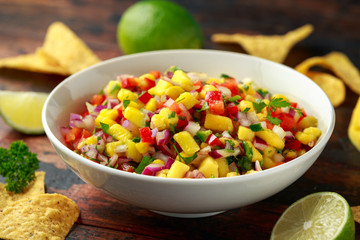 Bowl of fresh Mango Salsa with nachos chips and herbs. Healthy Vegan, Vegetables food.