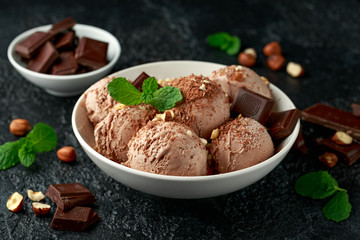 Chocolate Ice Cream with dark chocolate bars and hazelnuts in a white bowl