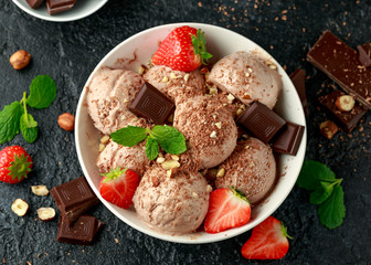 Chocolate Ice Cream with dark chocolate bars, strawberry and hazelnuts in a white bowl