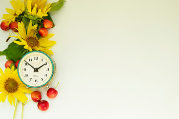 Autumn background. Border of yellow sunflower flowers, red apples and alarm clock. School concept, proper nutrition. There is a place for text.