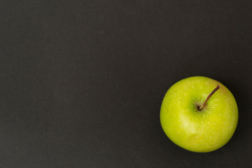 Green apple on a black background, chalk board, there is a place for text. Healthy eating concept.