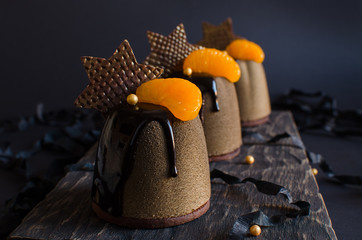 Contemporary chocolate and orange mousse mini cakes decorated with chocolate stars on dark background