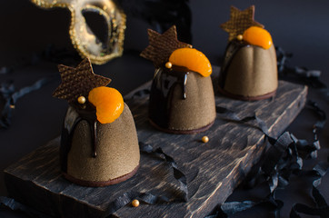 Contemporary chocolate and orange mousse mini cakes decorated with chocolate stars on dark background