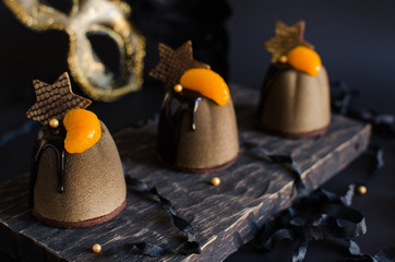 Contemporary chocolate and orange mousse mini cakes decorated with chocolate stars on dark background