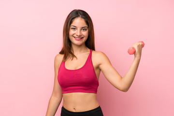 Young sport girl over isolated pink background making weightlifting