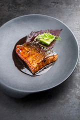 Minimalistic design Japanese salmon fish filet with vegetable and nori glazed in teriyaki sauce as closeup on a modern design plate