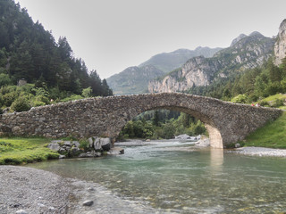 Fototapeta na wymiar Romanesque bridge of San Nicolás de Bujaruelo in the Bujaruelo valley. National Park of Ordesa and Monte Perdido in the Pyrenees of the province of Huesca. Aragon. Spain