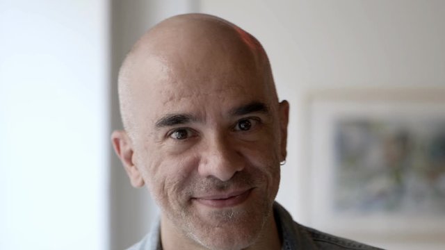 Handsome serious bald man posing. Middle aged man wearing casual shirt, looking at camera. Home male portrait concept