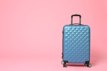 Stylish blue suitcase on pink background. Space for text