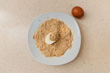 cocinando la receta de huevos rellenos de atún y mayonesa. en un plato se ve la mezcla y encima una mitad de huevo con el relleno. al lado hay un huevo con cáscara