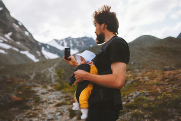 Father with baby carrier hiking in mountains travel family adventure vacations with kids healthy lifestyle outdoor in Norway blogger influencer modern online technology