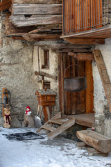 Old handmade dolls as decoration  near door of old alps building